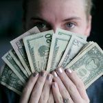 person holding fan of U.S. dollars banknote