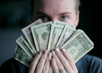 person holding fan of U.S. dollars banknote