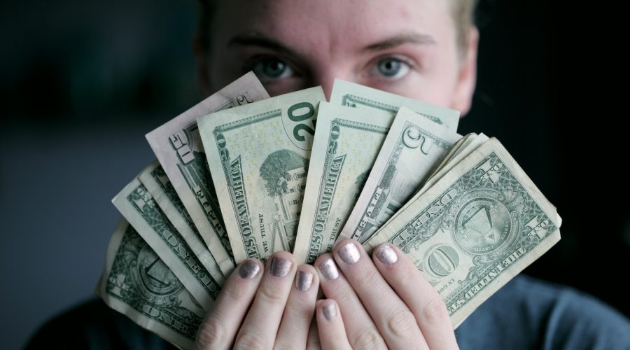 person holding fan of U.S. dollars banknote